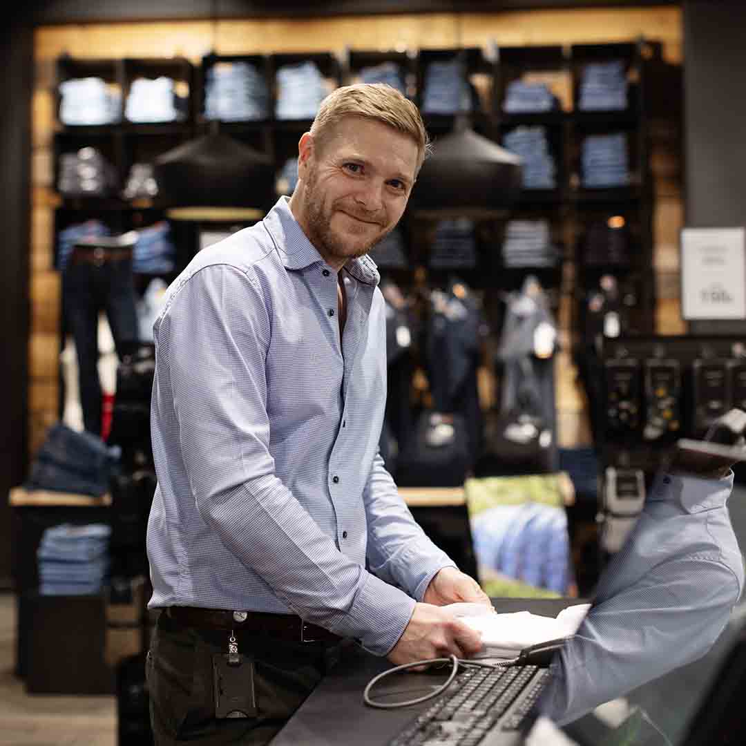 Smiling employee from Tøjeksperten in Frederiksberg.